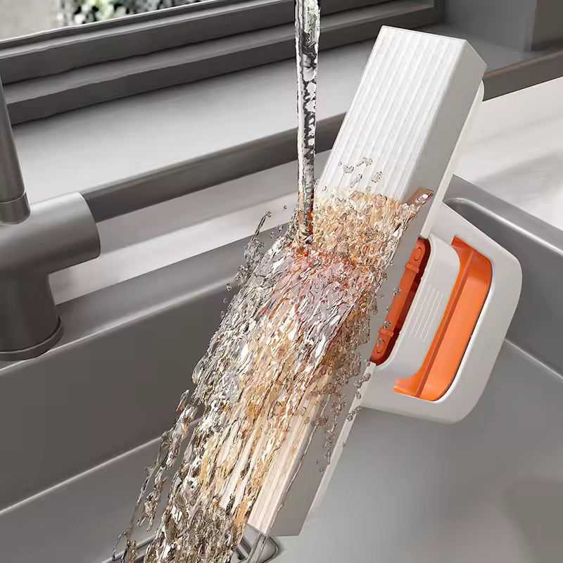 Cleaning tool with water flowing over it, likely a squeegee or similar device, in a kitchen setting.