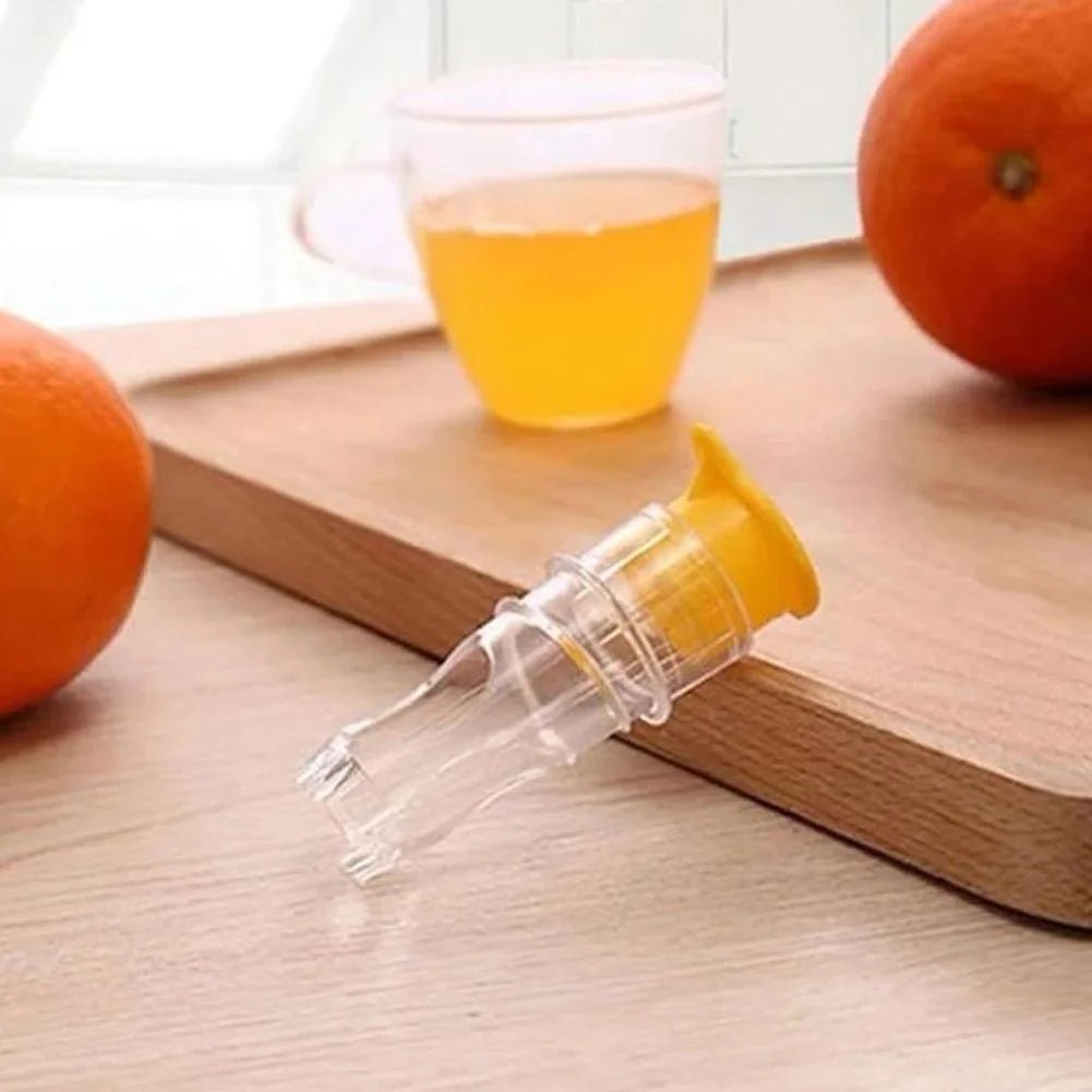 Orange juicer on a wooden cutting board with oranges and a glass of orange juice in the background.
